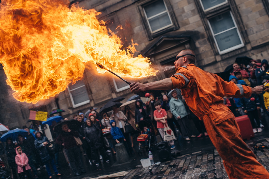 A fire breather performing before a crowd on an Edinburgh street